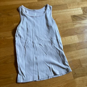 Beige linnetopp från 157 - En basic beige linnetopp från 157 i mjuk och skön bomull. Modellen är ärmlös med klassisk rund halsringning. 