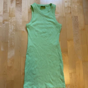 Grön ribbad kort klänning Bershka - Snygg ljusgrön ribbad klänning från Bershka i storlek S. Modellen är ärmlös med rund hals och tight passform som framhäver figuren. Perfekt för dig som gillar enkel och fräsch stil. Materialet är mjukt och stretchigt, vilket gör den superbekväm.