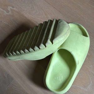 Limegröna Adidas slides med räfflad sula - Chunky slides från Adidas i limegrönt med bred rem över foten och öppen tå. Snygg, futuristisk design med kraftigt räfflad sula för extra grepp. Tillverkade i syntetmaterial och perfekta för chill dagar eller stranden. HAR TYVÄRR INTE BOX 