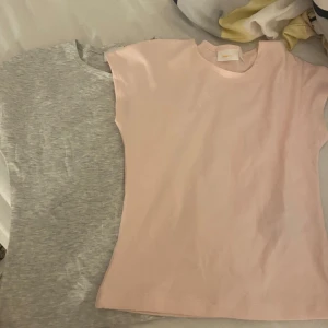 2-pack t-shirts från Gina Tricot - Två basic t-shirts från Gina Tricot i storlek 146/152. En är ljusrosa och den andra är ljusgrå, båda med rund hals och korta ärmar. Perfekta till jeans eller shorts, riktigt sköna och enkla att matcha. Materialet känns mjukt och stretchigt, troligtvis bomull.