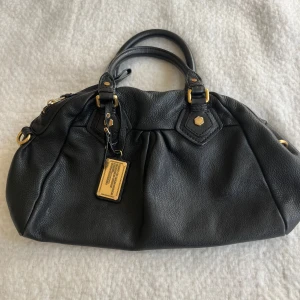 Svart handväska från Marc by Marc Jacobs - Säljer denna jätte fina svart handväska i äkta skinn från Marc by Marc Jacobs med guldfärgade metalldetaljer och dubbla handtag. Väldigt bra kvalité 💕