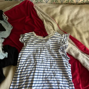 Randig topp med volangärm från SHEIN - Säljer en vit och blå randig topp från SHEIN i storlek M. Toppen har korta volangärmar och rund halsringning. Perfekt för dig som gillar en chill och söt stil. Materialet är mjuk bomull som känns skönt mot huden.