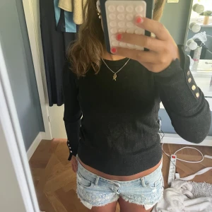 tröja med knappar - Snygg tröja med lång ärm och coola guldiga knappar på ärmsluten. Tröjan har en normal passform och är perfekt för dig som gillar stilrena och enkla plagg med en liten twist. Passar till jeans, kjol eller shorts.