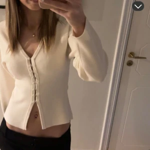 Vit croppad topp med knappar - Snygg vit croppad topp med lång ärm och v-ringning. Knappt använd så inga synliga effekter💗