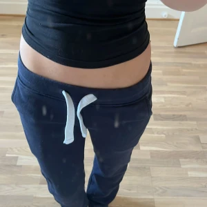 Mörkblå mjukisbyxor med snörning XXS - Mörkblå mjukisbyxor i storlek XXS från R. Byxorna har vit snörning i midjan och är gjorda i mjukt bomullsmaterial. Perfekta för chill dagar eller när du vill vara extra bekväm. Klassisk passform med resår i midjan.