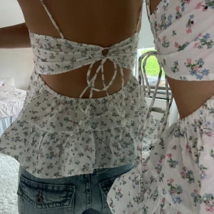 Blommig volangtopp med öppen rygg - Supersöt blommig topp med volanger från Gina som inte säljs längre. Toppen har öppen rygg med knyt och volangkant nertill. Eftersom man kan välja storlek själv så passar den mig som vanligtvis har xs i toppar, men passar även upp till storlek M🫶