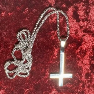 Nytt halsband med inverterat kors i blankt rostfritt stål – Ockult Wicca Alternativ - Halsband i rostfritt stål med inverterat kors – perfekt för goth, punk, metal och alternativ stil. Korset är ca 5 × 2,5 cm och kedjan ca 58 cm lång. Tåligt, blankt och håller sin finish över tid. Passar både till vardags och scen. Prutning accepteras inte, men jag erbjuder gärna rabatt vid köp av flera saker. Jag rensar smyckesskrin och garderob – kolla mina andra annonser!