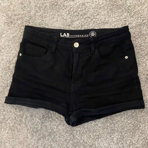 Svarta jeansshorts - Svarta jeansshorts från LAB Industries med klassisk femficksdesign, uppvikta benslut och bälteshällor. Snygg midwaist-modell som passar perfekt till sommaren. Stilrena och enkla att matcha med allt. 🩷