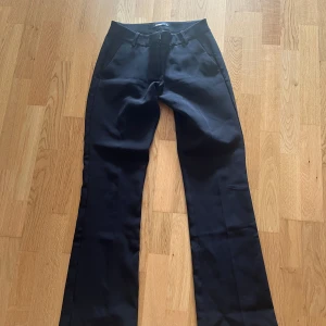 Svarta bootcut kostymbyxor BikBok - Snygga svarta kostymbyxor från BikBok i bootcut-modell. Byxorna har en låg midja, bälteshällor och dragkedja framtill. Perfekta för en clean och stilren look. Materialet är slätt och känns bekvämt mot huden. Använt fåtal gånger eftersom dom är för små för mig ❤️pris kan diskuteras ❤️