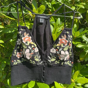 Broderad svart linnetopp - Svart linnetopp från Forever 21 med broderade blommor. Materialet är lätt och luftigt. Tycker att den passar som en M/L.