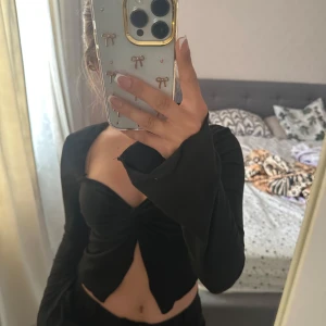 Svart croppad topp strl XS - Skickar iväg samma dag eller dagen efter🙌🏼Svart långärmad croppad topp från SHEIN med snygg twistad detalj framtill och lätt v-ringad urringning. Toppens material är stretchigt och följsamt, perfekt för att skapa en trendig look. Ärmarna är långa och toppen har en figurnära passform.