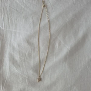 Guldigt halsband med stjärnhänge - Snyggt halsband i guldfärg med en tunn kedja och ett stjärnformat hänge. Perfekt för dig som gillar minimalistiska smycken med en cool detalj. Justerbar längd med förlängningskedja. Passar till alla outfits och ger en trendig touch.