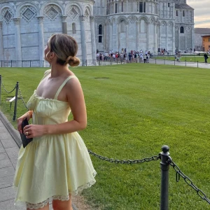 Ljusgul kort klänning med spets - Supersöt ljusgul klänning med kort längd och spetsdetaljer längs kanterna. Klänningen har smala axelband, snörning framtill och en voluminös kjol som ger en romantisk vibe. Perfekt för varma dagar och har en feminin, trendig look med omlottliknande överdel. Använd en gång! Superbra skick 🥰 skickar omgående 