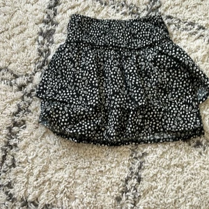 Svart blommig volangkjol från Zara - Supersöt svart kortkjol från Zara med vitt blommigt mönster❤️. Kjolen är i mycket bra skick och pris kan diskuteras❤️