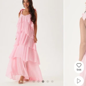 Ljusrosa volangklänning med rosetter - Superfin långklänning i ljusrosa med flera lager volanger och breda axelband som knyts i stora rosetter. Man kan knyta om banden och därför knyta den exv. i nacken om man vill. Klänningen har öppen rygg och är ärmlös. 🩷Priset går att diskutera. Jag är 161 och klänningen blir perfekt om jag har klackar på mig!