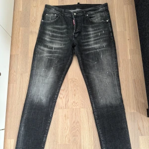 Svarta Dsquared2 jeans - Snygga svarta jeans från Dsquared2 med slitna detaljer och tvättad look. Modellen med klassiska fem fickor och läderpatch bak i midjan. Jeansen har en cool, mörkgrå färgton och är tillverkade i stretchig bomull för skön passform.