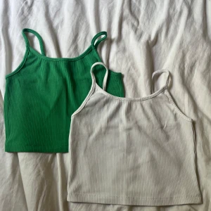 Ribbat grönt och vitt linne - Två stilrena ribbade linnetoppar i grönt och vitt med smala axelband. Croppad modell som sitter snyggt och är superbekväm under varma dagar.