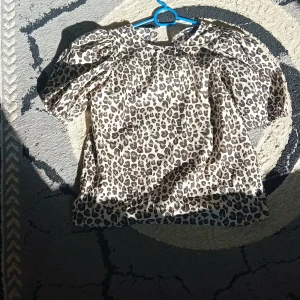 Leopardmönstrad blus med puffärm - Snygg blus med leopardmönster och puffiga korta ärmar. Toppen har en lös passform och rund halsringning. Perfekt för dig som vill sticka ut med ett djurmönster och volym i ärmarna.