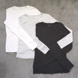 3-pack långärmade tröjor från H&M - Tre basic långärmade tröjor från H&M i storlek Xxs/Xs. En vit, en ljusgråmelerad och en svart. Alla har rund hals och är gjorda i mjuk bomull, perfekt för layering eller chill dagar. Snygg passform som sitter skönt mot kroppen. 