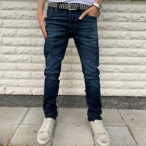 Mörkblå jeans Jack & Jones Storlek 28/32 - Snygga mörkblå skinny jeans från Jack & Jones med klassisk femficksdesign och diskreta sömmar. Jeansen har en smal passform och är tillverkade i stretchig denim för extra komfort. Perfekta till sneakers och t-shirt för en clean look. Jeansen är i riktigt fint skick. Priset är inte hugget i sten!