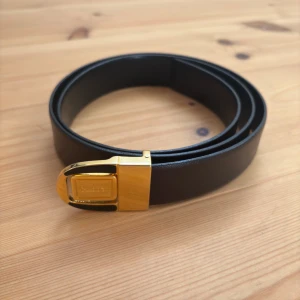 Vändbart svart/brunt bälte från Bally, guldspänne - Endast använt ett fåtal gånger  Svart och brunt vändbart äkta läder  Ursprunglig storlek är 105 cm (bältesänden till det originella mittersta hålet) men extra hål har lagts till för att passa mig (storlek 33”-34”), vilket gör det runt 90 cm. Se bild.  Gyllene Bally-spänne Köpt i Milano