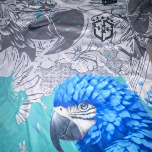 Nike Brasil CBF Dri-Fit fotbollströja S Limited Edition - Säljer en unik Brasil CBF fotbollströja från Nike i storlek S. Tröjan har ett färgstarkt tryck med blå papegoja, blommor och geometriska mönster i vitt, grått och turkos. Rund hals och korta ärmar. Materialet är lätt och andas med Dri-Fit teknologi.