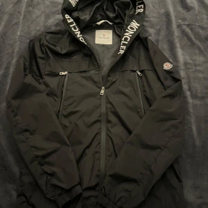 Svart vindjacka från Moncler - Sjukt snygg windbreaker de enda felet är en pytte liten fläck på andra bilden som kanske kan gå bort vet inte men syns inte när man har på sig den. Pris inte hugget i sten