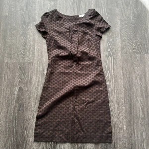 Brun prickig kortklänning Topshop - Snygg kort klänning från Topshop i brun med svarta prickar. Modellen har rund hals, korta ärmar och figurnära passform. 