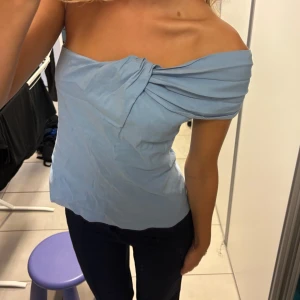 Ljusblå offshoulder topp med knut - Supersnygg ljusblå offshoulder topp med en cool knutdetalj framtill. 