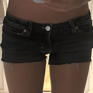 Mörkblå jeansshorts med rosett Monki - Snygga mörkblå jeansshorts från Monki med broderade rosetter på bakfickorna. Dom är lågmidjade och är i storlek 26. Dom säljs pågrund av att dom är lite förstora för mig och inte kommer till användning. Några av bilderna är lånade den sista bilden är lånad. 