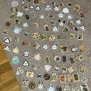 94 stycken klistermärken  - Bilden visar en samling klistermärken med motiv som böcker, fjärilar, blommor, svampar, djur och naturinspirerade illustrationer. Det är ingen bok på bilden, utan dekorationer som passar för att pynta anteckningsböcker, dagböcker eller laptops.