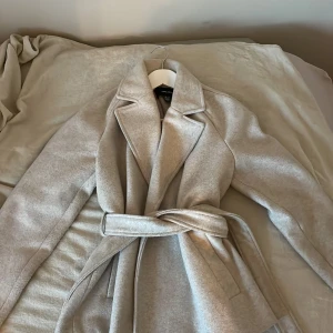 Beige kappa med bälte från Vero Moda - Säljer min beiga kappa från vero Moda. Använd antal gånger o är ganska nopprig.