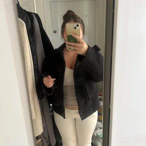 Svart ulljacka från 157, storlek M - Säljer en svart, kortare ulljacka från 157 i storlek M. Jackan har klassisk krage, stora knappar framtill och två fickor. Perfekt för dig som gillar en stilren och enkel look med lite boxig passform.