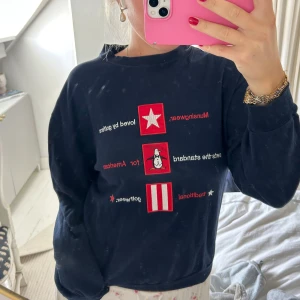 Mörkblå sweatshirt med broderi - Mörkblå sweatshirt från Original Penguin med broderade detaljer i rött, vitt och gult framtill. Tröjan har rund hals, långa ärmar och en relaxed passform. 