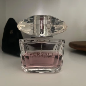 Versace Bright Crystal parfym 90ml - Versace Bright Crystal Eau de Toilette i en lyxig, transparent glasflaska med diamantformad kork. Innehåller 90 ml ljusrosa parfym. Flaskan har eleganta linjer och känns riktigt exklusiv – perfekt för dig som gillar stilrena och feminina dofter.