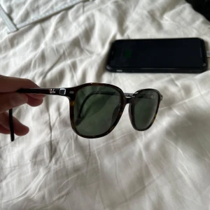 Ray-Ban Leonard brunmelerade solglasögon - Snygga Ray-Ban Leonard RB2193 solglasögon med brunmelerad båge och gröna glas. Klassisk rundad form och diskret logga på linsen. Tillverkade i Italien och passar perfekt för dig som vill ha en tidlös och cool look.