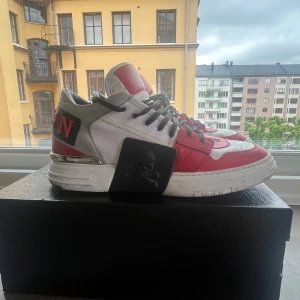 Philipp Plein sneakers röd/vit/svart - Snygga sneakers från Philipp Plein i rött, vitt och svart skinn med coola detaljer som dödskalle, broderad logga och siffrorna 1978 på tårna. Skorna har svarta snören, platt sula och silverdetaljer på hälen. Perfekt för dig som vill sticka ut. (Säljs inte längre)