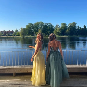 Ljusgul långklänning med öppen rygg - Superfin ljusgul långklänning med halterneck och öppen rygg. Klänningen har tunna axelband med små pärlor, flowigt fall och slits framtill. Perfekt för bal eller andra festligheter 🌟🎉                                   Jag är 168 cm lång, men har sytt upp klänningen i längden (går enkelt att förlänga igen) skriv gärna om du har fler frågor om mått eller liknande!