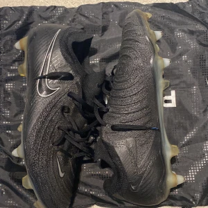 Nike Phantom GX/LUNA Elite SG - Säljer nu ett par svarta Nike phantom Gx elite, de är lite användbara vilket man ser på undersidan av skorna men annars i toppenskick. Originallåda tillkommer ej. Hör gärna av er vid eventuella frågor. Priset är ej hugget i sten! MVH Nils