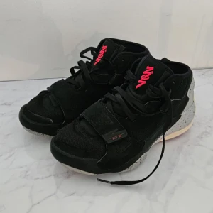 Nike Jordan sneakers svart/grå/röd - Snygga Nike Jordan sneakers i svart och grått med röda detaljer och logga. Skorna har snörning, kardborreband och en cool, stänkmålad sula. Ovandelen är i textil och syntet, med rund tå och mellanhögt skaft. Perfekta för dig som gillar streetstyle och basketvibe.