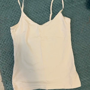 Vit linnetopp med smala axelband - Snygg vit linnetopp med smala, justerbara axelband och v-ringad hals. 