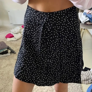 Svart prickig kjol från & Other Stories - Supersöt svart kortkjol från & Other Stories med vita prickar. Kjolen har en lätt A-linjeform och stängs med dragkedja i sidan. 