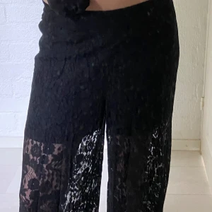 Svart byxor  - Säljer ett par svarta byxor i transparent spets med blommigt mönster. Byxorna har hög midja och ett loose, wide fit som ger en riktigt snygg siluett. Perfekta för dig som vill sticka ut med en unik och trendig look.