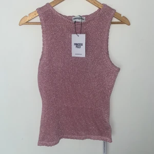 Glittrig ärmlös topp från Princess Polly - Ärmlös modell med rund halsringning och lätt croppad passform. Stickad känsla med stretchigt material och vågig kant nertill. Säljer den på grund av att den var lite liten för mig och istället för att betala mer för att returnera den, valde jag att sälja den. Ordinarie pris var 45$, vilket är ungefär 438kr. OBS! Tänk på att om man beställer från hemsidan hade det kostat mer pga tull och skatt (USA). Visar enbart priset för själva varan.
