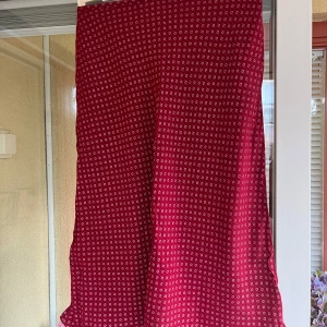 Röd kjol från Indiska - Säljer en röd kjol från Indiska med små vita blommönster. Kjolen har en dragkedja i sidan.. Perfekt för dig som vill ha något luftigt och snyggt till sommaren. Storlek S.