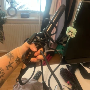 Svart och guldig locktång - Snygg locktång i svart och guld med digitala knappar för temperaturkontroll. Perfekt för att fixa mjuka lockar eller beach waves. Ergonomiskt handtag och lång sladd för smidig styling. Passar dig som vill ha salongskänsla hemma.