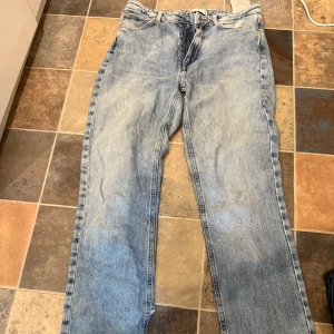 Ljusblå raka jeans från Zara - Säljer ett par ljusblå jeans från Zara med rak passform och råa, fransiga benslut med en slits nedtill. Klassisk femficksmodell med dragkedja . Jeansen har en avslappnad vibe, perfekta till sneakers eller boots. Obs att knappen till byxorna saknas men det är lätt att åtgärda (se 2 bilden)!!