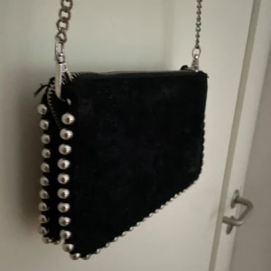 Svart väska från zara med silverdetaljer  - Säljer denna fina växla från zara. Den är svart med fina silverdetaljer på sidorna och ett långt silvrigt band. Väskan har tre fack. Skriv om ni har frågor och priset kan diskuteras💗🤗🌸😽💓🫶🏻