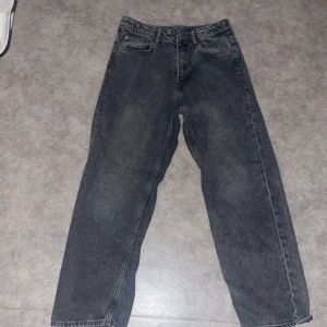 Svarta loose fit jeans från H&M - 12-13år Säljer ett par svarta loose fit jeans från H&M med justerbar midja. Jeansen har raka ben, klassisk femficksdesign och är tillverkade i denim. Perfekta för en avslappnad och trendig look.