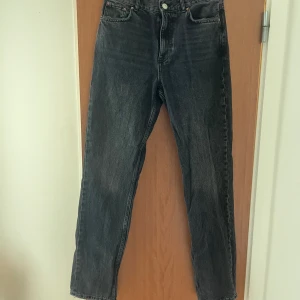 Svarta raka jeans med råa kanter - Snygga svarta jeans från Gina tricot med medel hög midja och raka ben. Jeansen har en tvättad look och sliten stil vid fickor och benslut, det var så när de köptes så det är inget slitage